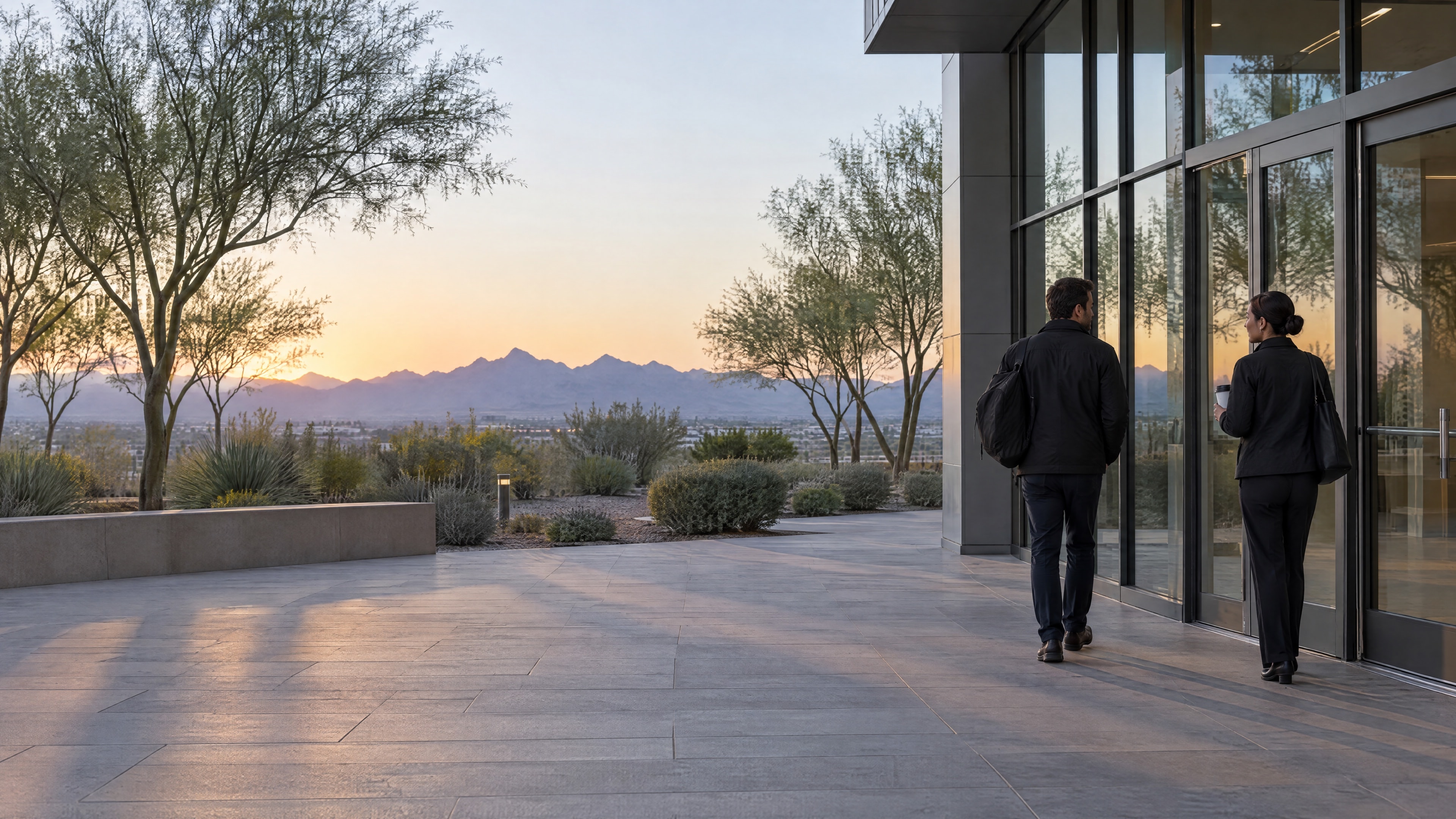 Two officers at the entrance of a building at dawn, one arriving and one heading home.